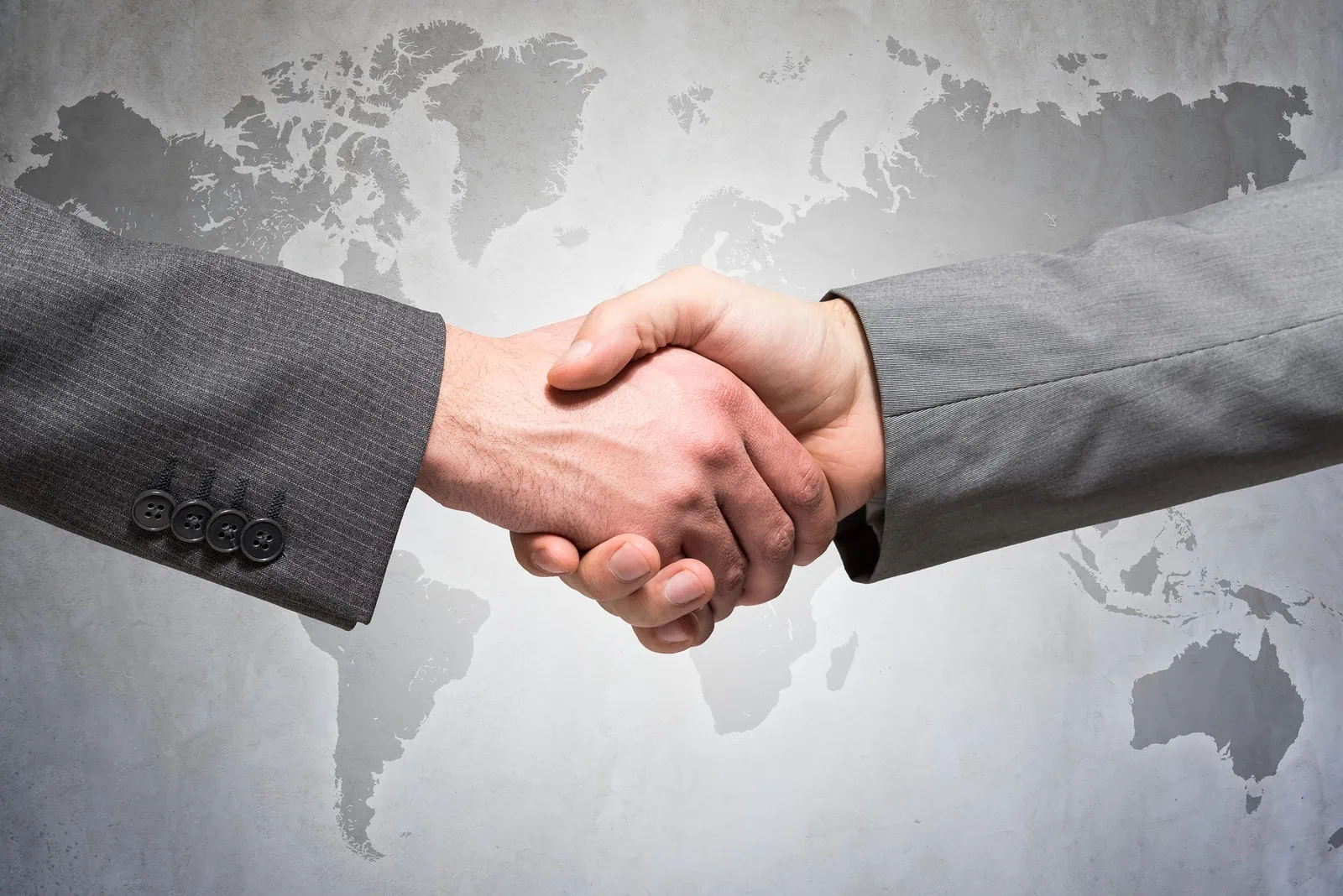 arms of two people in business suits shaking hands
